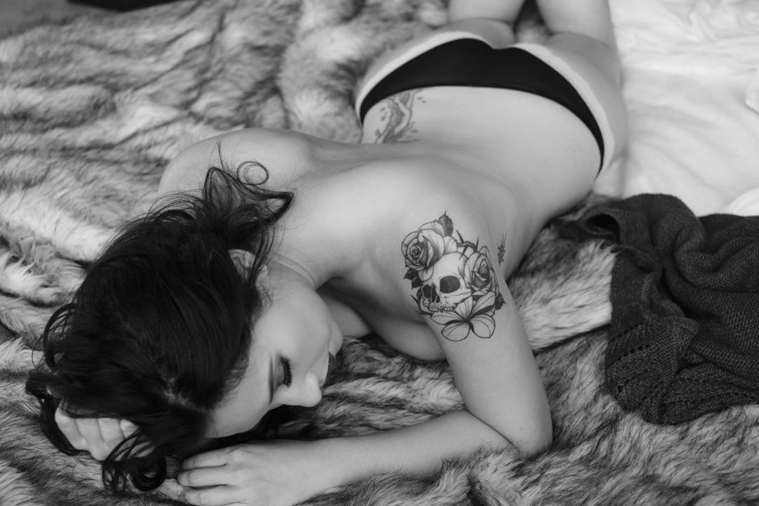 topless woman with tattoos lying on bed in toronto boudoir studio