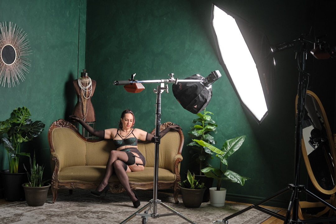 BTS behind the scenes of boudoir session in our Toronto Boudoir photography studio on green set with plants and model wearing green and black lingerie